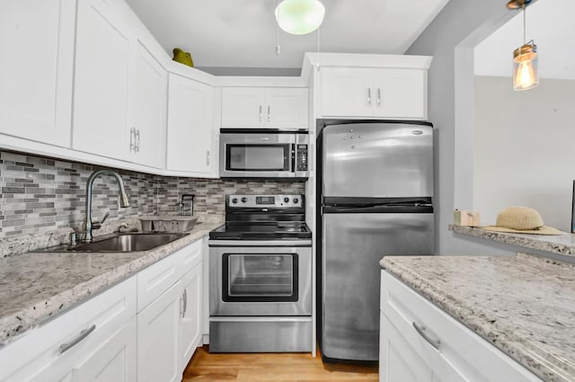 kitchen featuring hanging light fixtures, white cabinetry, sink, and appliances with stainless steel finishes