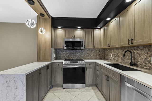 kitchen with light stone counters, stainless steel appliances, tasteful backsplash, a sink, and a peninsula