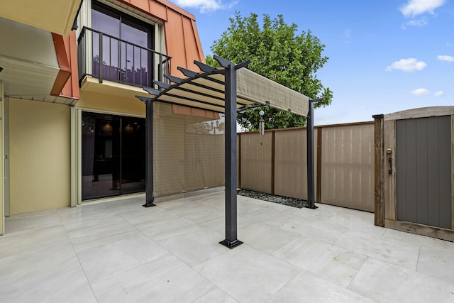 view of patio with fence, a balcony, and a pergola