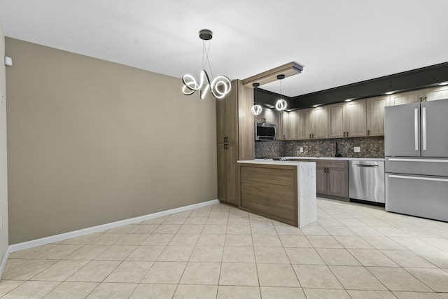 kitchen with stainless steel appliances, tasteful backsplash, light tile patterned flooring, a peninsula, and baseboards