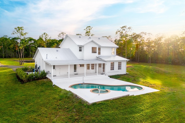 back of house featuring a pool with hot tub, a patio area, and a lawn