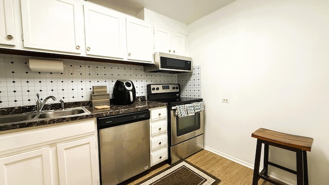 kitchen with sink, tasteful backsplash, light wood-type flooring, appliances with stainless steel finishes, and white cabinets