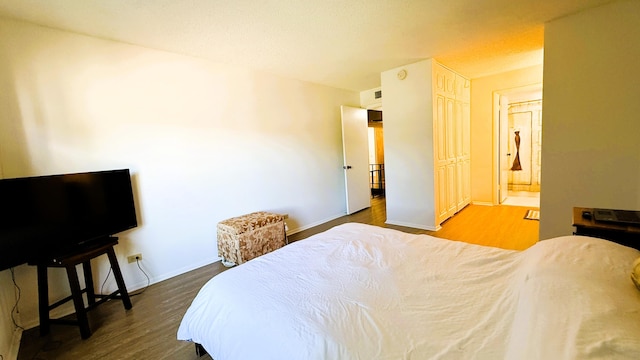 bedroom with connected bathroom and hardwood / wood-style flooring