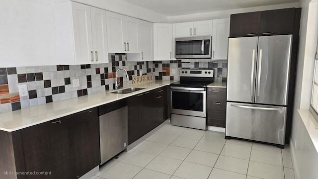 kitchen featuring decorative backsplash, appliances with stainless steel finishes, dark brown cabinets, sink, and white cabinets