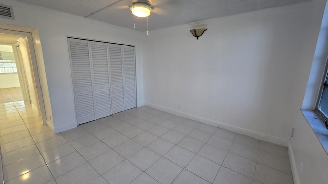 unfurnished bedroom featuring ceiling fan, a closet, and light tile patterned floors