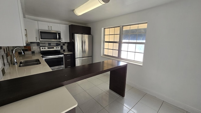 kitchen with backsplash, white cabinets, sink, light tile patterned floors, and appliances with stainless steel finishes