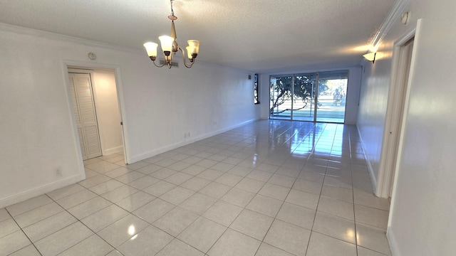 spare room with crown molding, light tile patterned floors, and a chandelier