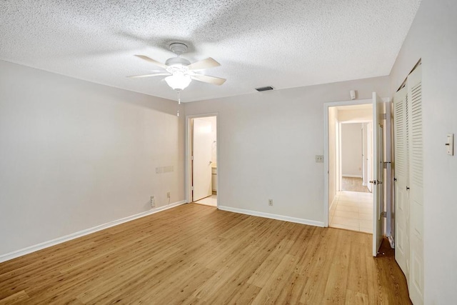 unfurnished bedroom with ceiling fan, a textured ceiling, and light wood-type flooring