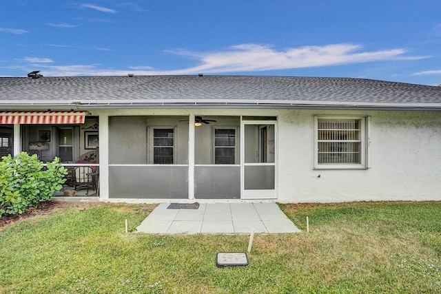 rear view of house with ceiling fan and a lawn