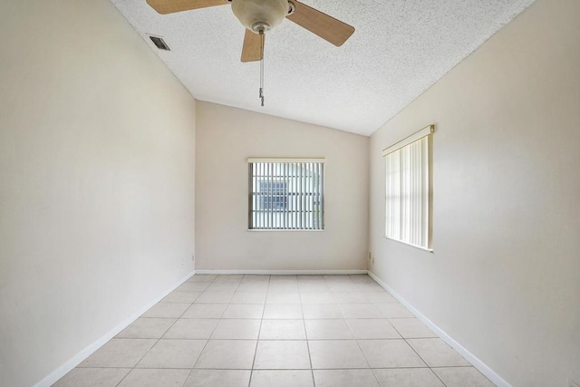 tiled empty room featuring a textured ceiling, ceiling fan, and lofted ceiling