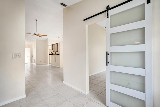 hall featuring light tile patterned floors, a barn door, and built in shelves