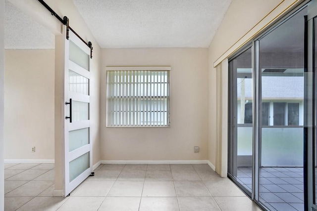 interior space with a barn door, light tile patterned flooring, and a textured ceiling