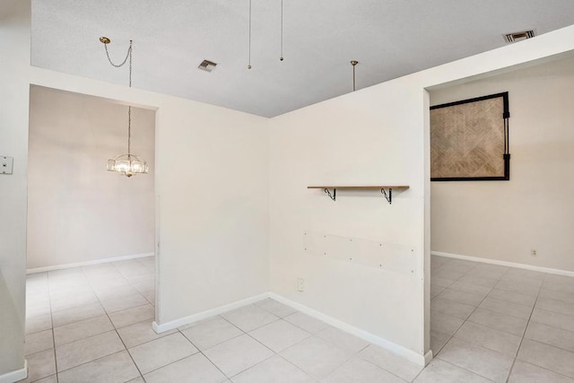 empty room featuring a notable chandelier and light tile patterned floors