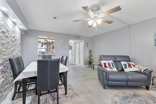 dining space featuring ceiling fan, light hardwood / wood-style floors, and a textured ceiling