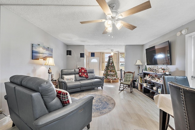 living room featuring a textured ceiling, light hardwood / wood-style floors, and ceiling fan