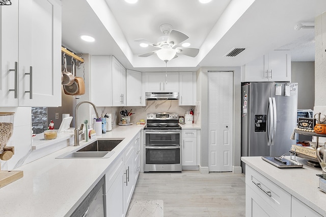 kitchen with appliances with stainless steel finishes, light wood-type flooring, ceiling fan, sink, and white cabinets