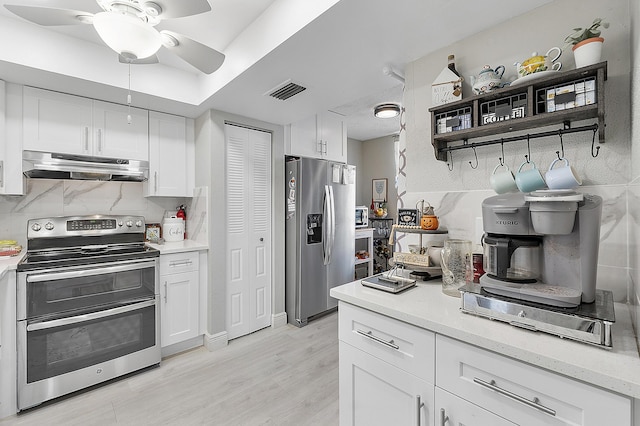 kitchen featuring white cabinets, ceiling fan, decorative backsplash, appliances with stainless steel finishes, and light hardwood / wood-style floors