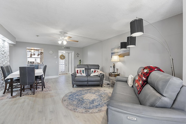 living room with ceiling fan, light hardwood / wood-style floors, and a textured ceiling