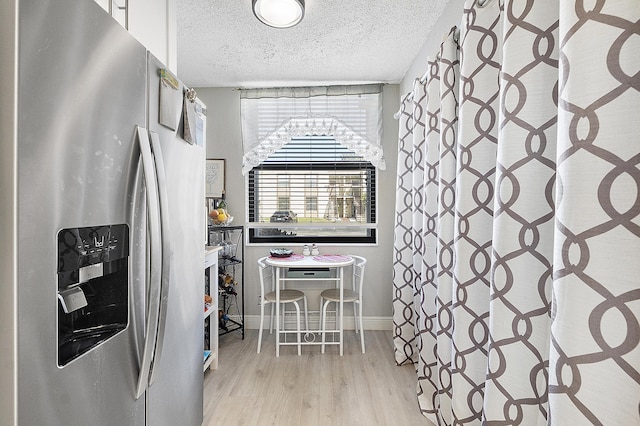 kitchen featuring a textured ceiling, white cabinetry, light hardwood / wood-style flooring, and stainless steel refrigerator with ice dispenser