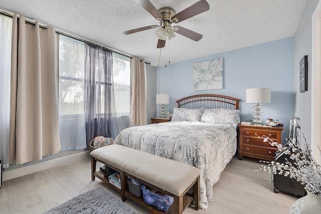 bedroom with ceiling fan, a textured ceiling, and light wood-type flooring