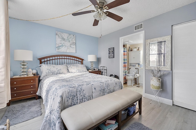 bedroom featuring a textured ceiling, ensuite bathroom, ceiling fan, and light hardwood / wood-style floors