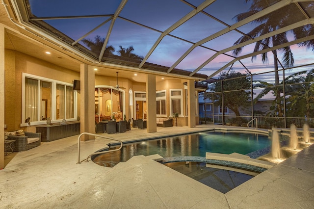 pool at dusk featuring outdoor lounge area, a patio area, a lanai, and an in ground hot tub