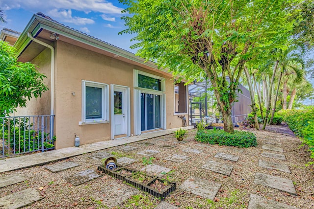 rear view of property featuring glass enclosure and a patio area