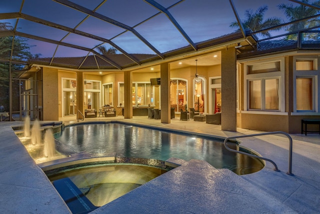 pool at dusk with an in ground hot tub, a patio, an outdoor living space, and glass enclosure