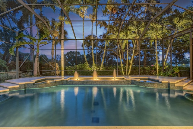 pool at dusk with glass enclosure and an in ground hot tub