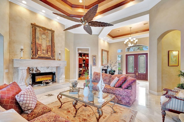 living room with a raised ceiling, ornamental molding, a high ceiling, and a premium fireplace