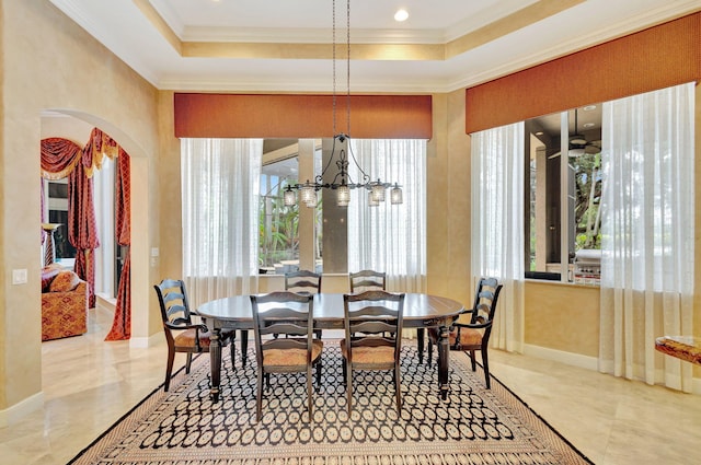 dining area featuring a notable chandelier, a raised ceiling, and crown molding