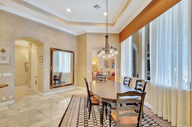 dining space featuring a notable chandelier, a raised ceiling, and crown molding