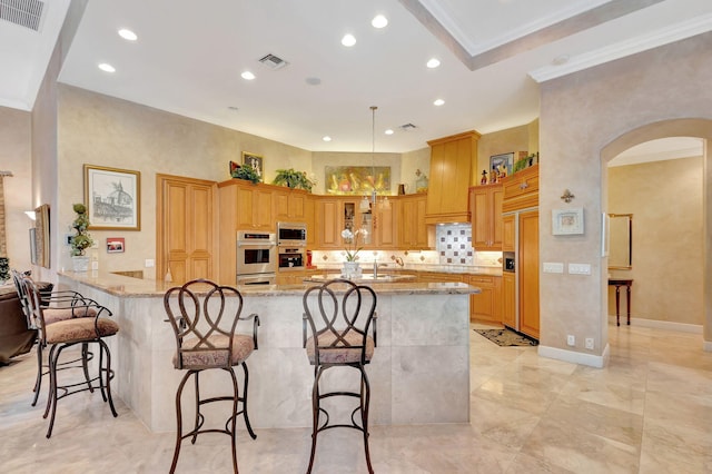 kitchen featuring kitchen peninsula, a breakfast bar area, appliances with stainless steel finishes, and ornamental molding