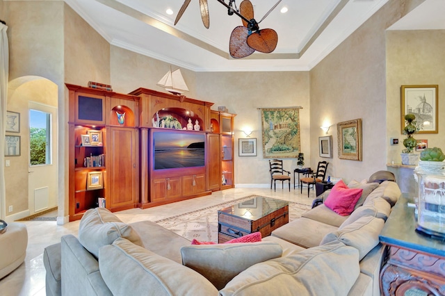 tiled living room featuring ceiling fan, a towering ceiling, and ornamental molding