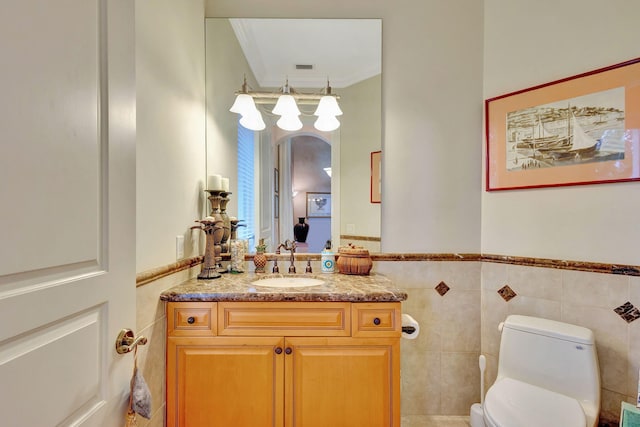 bathroom featuring vanity, toilet, crown molding, and tile walls