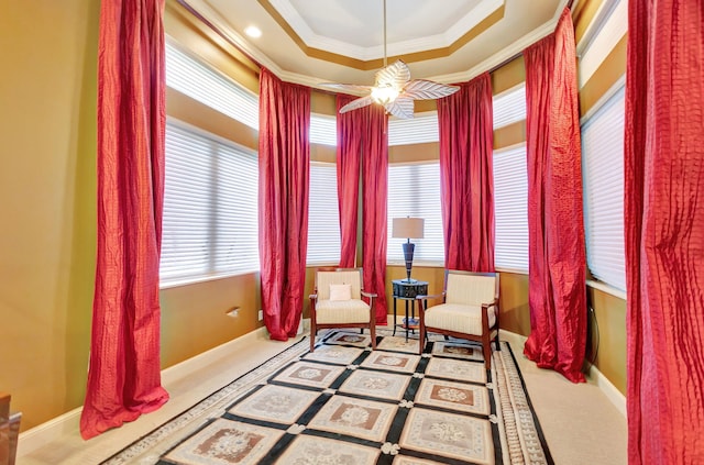 living area featuring carpet flooring, ceiling fan, and crown molding