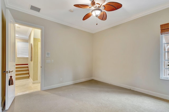 empty room with ceiling fan, crown molding, and light carpet