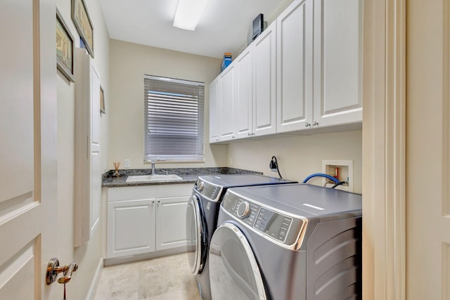 clothes washing area featuring washing machine and dryer, sink, and cabinets