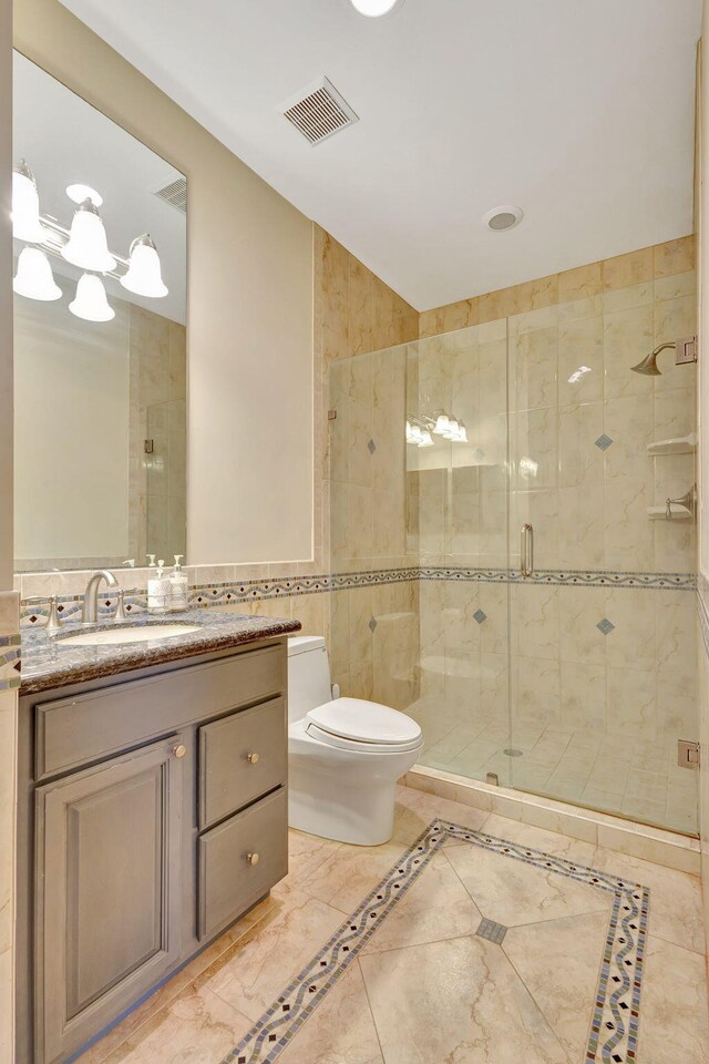 bathroom featuring vanity, a shower with door, toilet, and tile walls