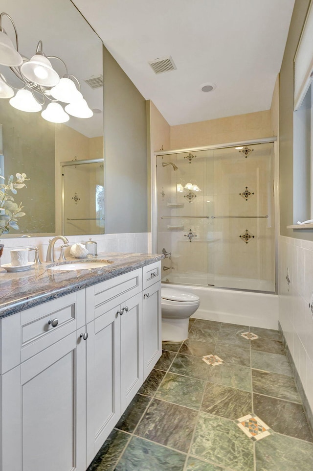 full bathroom with vanity, enclosed tub / shower combo, and toilet