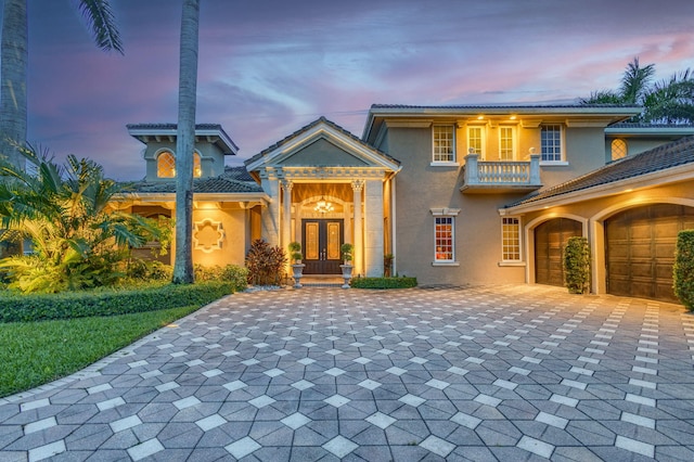 view of front of property with a balcony, french doors, and a garage