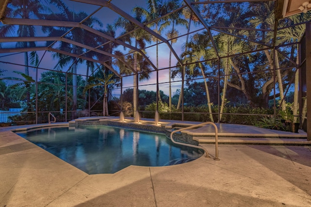 pool at dusk featuring glass enclosure and a patio