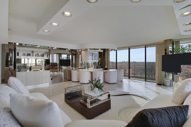 living room with a wall of windows and light tile patterned flooring