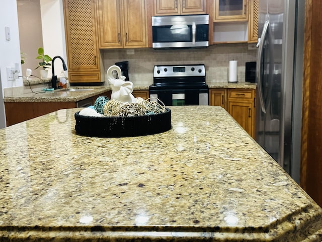 kitchen featuring backsplash, light stone countertops, and stainless steel appliances