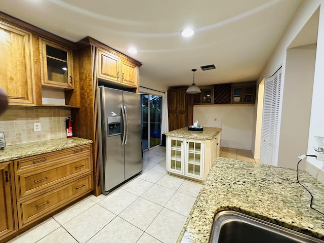 kitchen with sink, light stone countertops, stainless steel refrigerator with ice dispenser, and tasteful backsplash