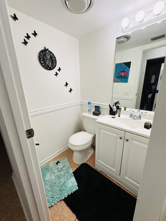 bathroom with toilet, vanity, and tile patterned floors