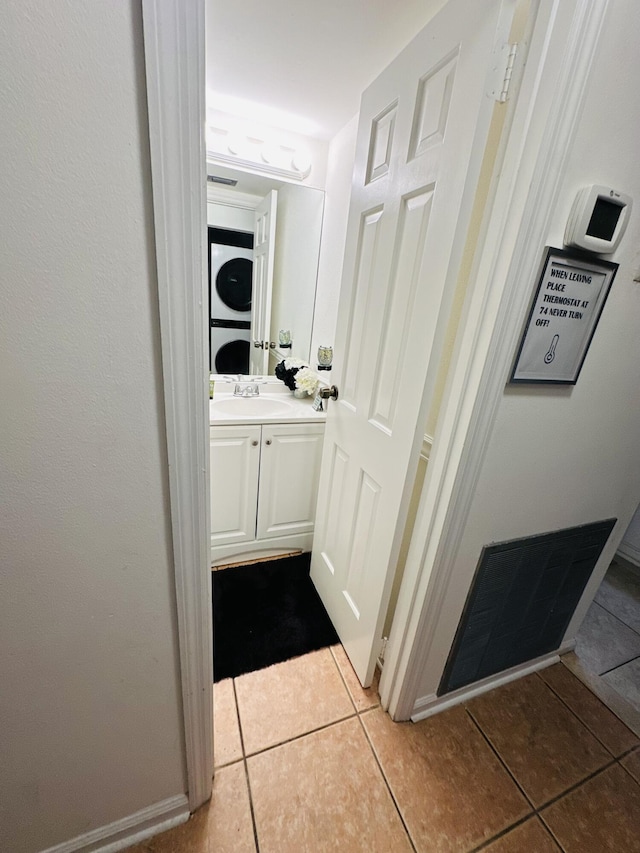 hallway featuring sink, stacked washing maching and dryer, and light tile patterned flooring