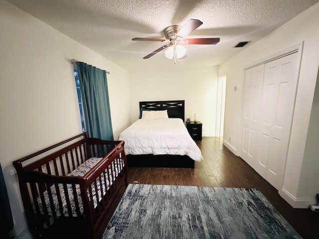 bedroom featuring a textured ceiling, dark hardwood / wood-style flooring, a closet, and ceiling fan