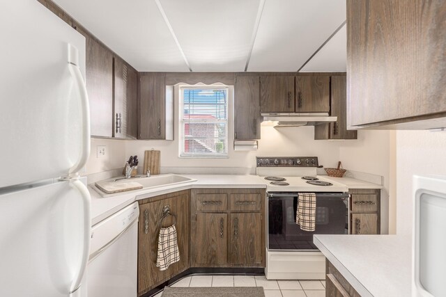 kitchen featuring dark brown cabinets, white appliances, sink, and light tile patterned floors