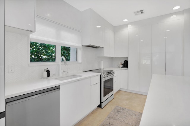 kitchen with white cabinetry, sink, stainless steel appliances, decorative backsplash, and light tile patterned floors